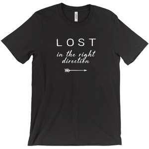 May include: Black t-shirt with the white text "LOST in the right direction" and an arrow pointing right. The shirt is a crew neck style and appears to be made of a soft material.