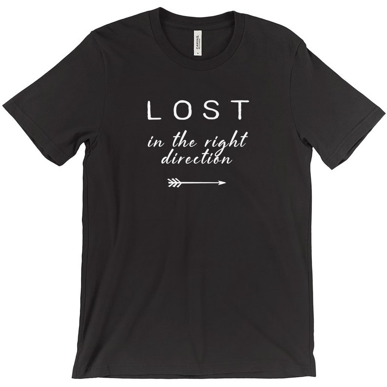 May include: Black t-shirt with the white text "LOST in the right direction" and an arrow pointing right. The shirt is a crew neck style and appears to be made of a soft material.