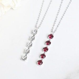 May include: Two silver necklaces with a chain design. One necklace has clear crystals and the other has red crystals.