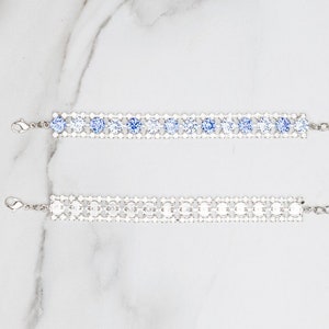 May include: Two silver bracelets with clear and blue crystal embellishments. The bracelets have a chain link extension.