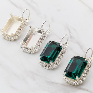 May include: Four pairs of earrings with silver settings and emerald green stones. The earrings have a clear crystal halo around the stones.