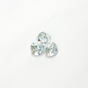 May include: Three clear glass rhinestones with a square shape and a faceted design.