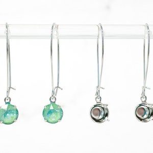 May include: Three pairs of silver earring findings with a green iridescent glass stone, a silver setting, and a silver hook.