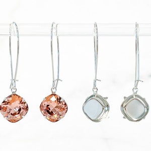 May include: A pair of silver dangle earrings with peach-colored square-shaped crystal stones. The earrings are shown from the front and back.