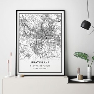May include: Black and white map print of Bratislava, Slovak Republic with the coordinates 48.1486° N | 17.1077° E. The print is framed and hanging on a white wall above a white shelf with a black top.