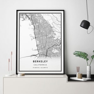 May include: Black and white map print of Berkeley, California with the city name and coordinates printed below the map. The print is framed and hanging on a white wall above a white and black console table.