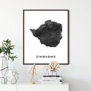 May include: A black and white watercolor print of the outline of Zimbabwe. The print is framed in a black frame and the word "Zimbabwe" is printed in black below the map.