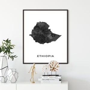 May include: Black and white print of a map of Ethiopia with a watercolor effect. The map is framed in a black frame and the word "ETHIOPIA" is printed below the map.