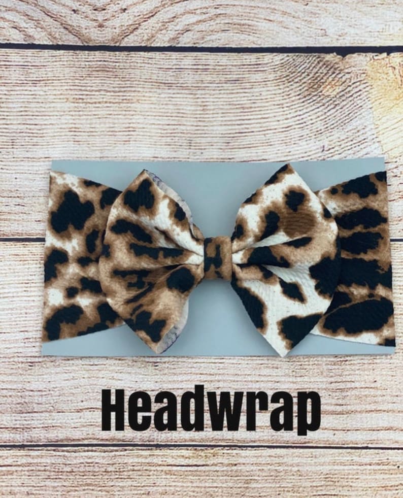 May include: A brown and black leopard print headband with a large bow. The headband is on a light gray background with the word "Headwrap" printed below it.