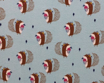 May include: A blue fabric with a repeating pattern of brown squirrels holding acorns. The squirrels are surrounded by a brown swirl design.