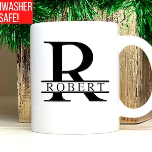 May include: White ceramic mug with a black letter "R" and the name "ROBERT" printed on it. The mug is dishwasher safe.