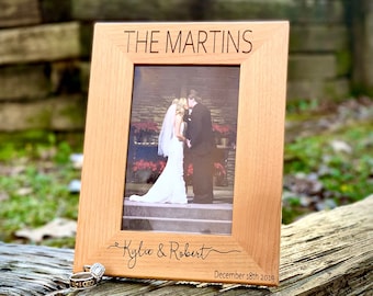 Könnte beinhalten: Ein Bilderrahmen aus Holz mit einem Hochzeitsfoto eines sich küssenden Paares. Der Rahmen ist mit "The Martins" oben, "Kylie & Robert" in Kursivschrift unter dem Foto und "December 18th 2019" unten graviert.