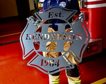 May include: A black metal firefighter's emblem with the text "Est. 1984" and the name "Henderson" in a stylized font.