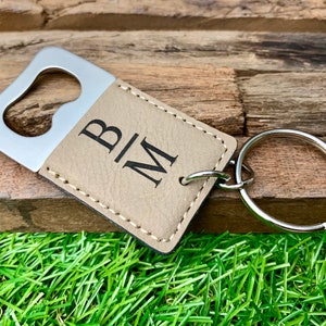 May include: A brown leather bottle opener keychain with a silver bottle opener and the initials "B|M" engraved on the leather.