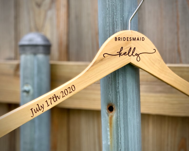 May include: Wooden hanger with the text "BRIDESMAID Kelly" and "July 17th 2020" engraved on it.