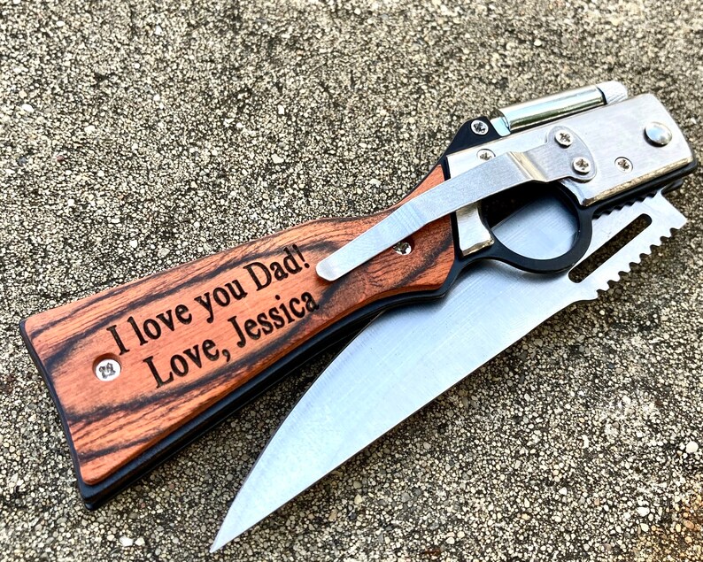 Puede incluir: Un cuchillo de bolsillo con mango de madera, una hoja de plata y una sierra. El mango est&aacute; grabado con las palabras "I love you Dad! Love, Jessica".