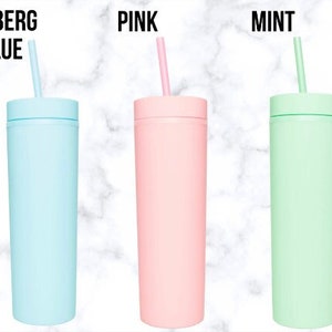 K&ouml;nnte beinhalten: Drei isolierte Becher in Pastellfarben: Eisbergblau, Pink und Mint. Jeder Becher hat einen passenden Strohhalm und einen Schraubdeckel. Der Text "ICEBERG BLUE", "PINK" und "MINT" ist &uuml;ber jedem Becher aufgedruckt.