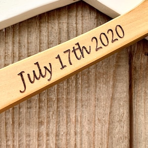 May include: Close-up of a wooden sign with the date "July 17th 2020" engraved on it.