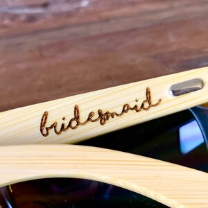 Pu&ograve; includere: Un paio di occhiali da sole in bamb&ugrave; con la parola "bridesmaid" incisa sulla montatura.