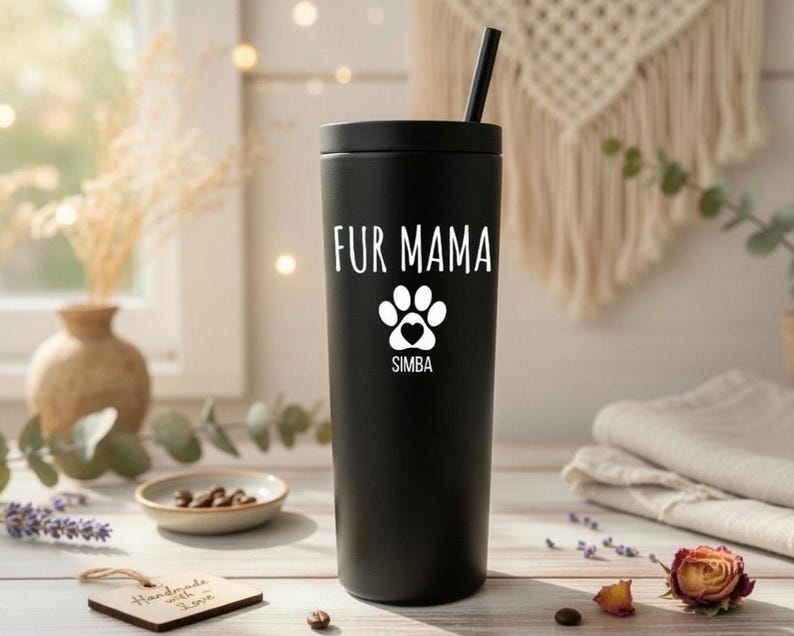 K&ouml;nnte beinhalten: Ein schwarzer Becher mit Strohhalm, mit dem wei&szlig;en Text "FUR MAMA", einem Pfotenabdruck-Design und dem Namen "SIMBA". Der Becher ist zylindrisch und vermutlich aus Edelstahl, geeignet f&uuml;r Getr&auml;nke.