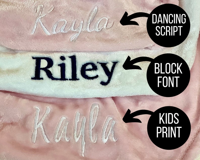 May include: Three pink and white blankets with the name "Kayla" embroidered in different styles. The top blanket has the name in a cursive script font, the middle blanket has the name in a block font, and the bottom blanket has the name in a kids print font.