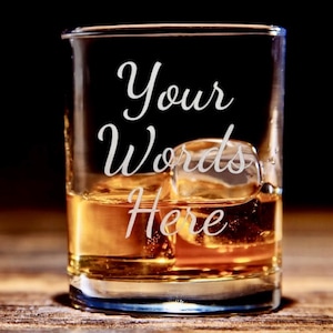 May include: A white ceramic mug with a black handle and the text "But first, coffee" in a black, handwritten-style font. The mug is on a white surface.