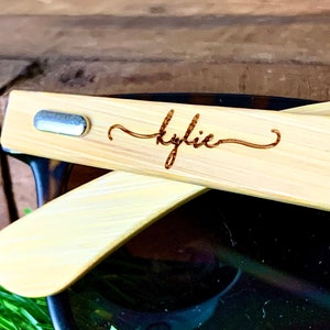 Pu&ograve; includere: Un paio di occhiali da sole in bamb&ugrave; con un accento in metallo argentato sul braccio. Gli occhiali da sole sono personalizzati con il nome "Kylie" inciso sul braccio.