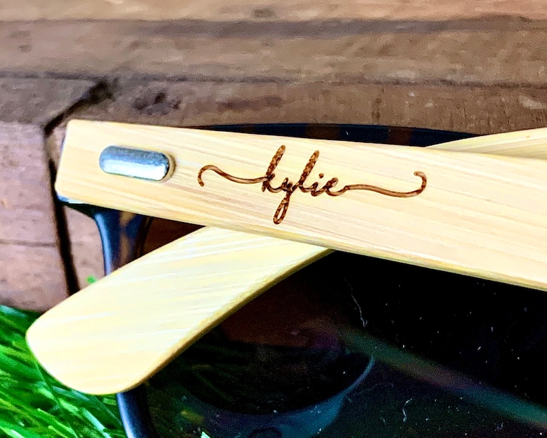 Pu&ograve; includere: Un paio di occhiali da sole in bamb&ugrave; con un accento in metallo argentato sul braccio. Gli occhiali da sole sono personalizzati con il nome "Kylie" inciso sul braccio.