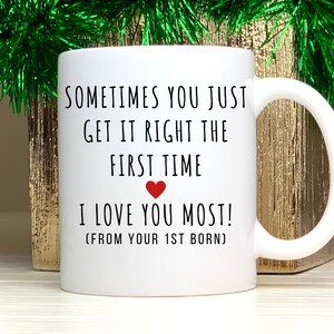 May include: White ceramic mug with black text that reads "Sometimes you just get it right the first time. I love you most! (From your 1st born)". A red heart is between the text "first time" and "I love you most!"