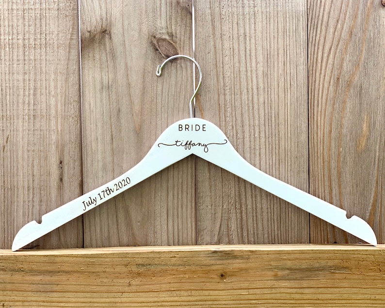 May include: White wooden hanger with the word "BRIDE" and the name "tiffany" written in cursive. The date "July 17th, 2020" is written below the name.