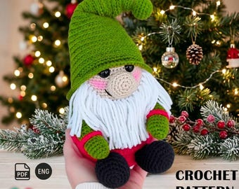 May include: A crocheted gnome doll with a green hat, white beard, and red and green clothing. The gnome has a beige nose and black eyes. The doll is held in a hand in front of a Christmas tree. The text "CROCHET PATTERN" is visible.
