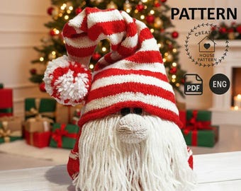 May include: A knitted gnome with a red and white striped hat and a long white beard. The gnome has a round nose and black eyes. The image includes the text "KNITTING PATTERN" and a logo with the words "CREATE HOUSE PATTERN".