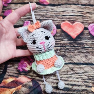 Peut inclure: Ornement de chat au crochet fait &agrave; la main en gris, orange et vert. Le chat a un nez rose et un petit n&oelig;ud orange. Le chat porte une robe verte et orange. Le chat est suspendu &agrave; une ficelle blanche.