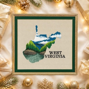 May include: Framed cross-stitch art featuring the outline of West Virginia, with a bridge and mountain scene. The state name is stitched in black. The artwork is in a green frame, surrounded by holiday decorations.