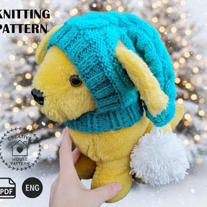 May include: A yellow plush dog toy wearing a teal knitted hat with a white pom-pom tail. The words "KNITTING PATTERN" are at the top of the image. The image also includes the words "CREATIVE HOUSE PATTERN", "PDF", and "ENG".