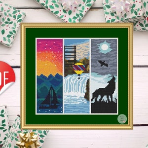 May include: Cross stitch pattern featuring four different scenes: a sunset over mountains with a sailboat, a waterfall with a hot air balloon, a night sky with a wolf howling at the moon, and a bird flying overhead. The pattern is framed in a gold frame with a green mat.