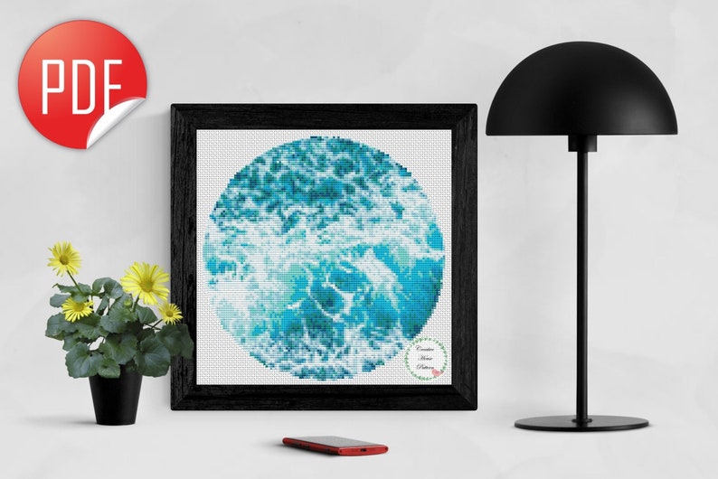 May include: A framed cross-stitch pattern of a blue and white ocean wave design. The design is circular and the text "Creative Home Patterns" is in the lower right corner.