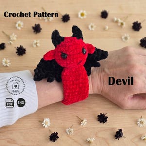 May include: A red and black crocheted devil wrist accessory featuring small horns and wings. The text Crochet Pattern and Devil are visible. A circular logo with a house icon and the text Creative House Pattern, along with PDF and ENG icons, are present.