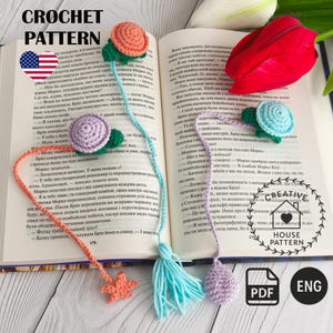 Könnte beinhalten: Häkelanleitung mit handgefertigten Lesezeichen mit Blumen- und Sternmotiven. Die Lesezeichen sind in Orange, Lila und Blau gehalten und auf einem offenen Buch platziert. Der Text "CROCHET PATTERN" steht oben.