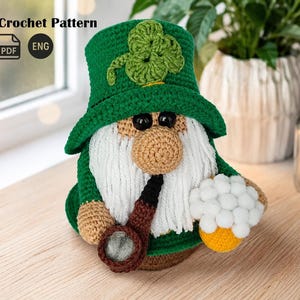 May include: A crocheted gnome wearing a green hat with a shamrock, holding a mug of beer and a pipe. The gnome has a white beard, a tan nose, and black eyes. The image includes the text "Crochet Pattern" and the PDF and ENG icons.