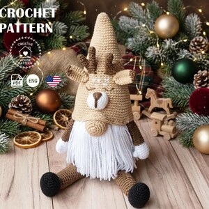 Könnte beinhalten: Eine Häkelanleitung für einen Rentier-Wichtel mit dem Text CROCHET PATTERN, CREATIVE HOUSE PATTERN, PDF und ENG. Der Wichtel hat eine beige spitze Mütze mit braunem Geweih, eine weiße Schnauze, eine runde Nase und einen langen weißen Garnbart.
