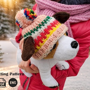 May include: A plush dog toy wearing a colorful knitted hat with a pom-pom. The hat features stripes of pink, green, yellow, and red. The dog has brown ears and a black nose. The image includes the text "Knitting Pattern" and "ENG".
