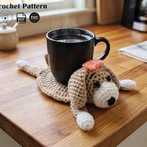 A crochet pattern for a puppy dog coaster. A steaming black mug sits on a handmade light brown and white crocheted dog-shaped coaster on a wooden countertop.
