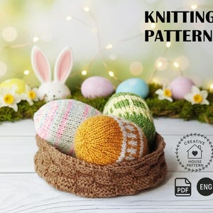 Op de afbeelding: Een bruine geweven mand bevat vier gebreide paaseieren in tinten roze, geel, groen en wit. De achtergrond toont een witte konijn, paaseieren en de tekst "KNITTING PATTERN".