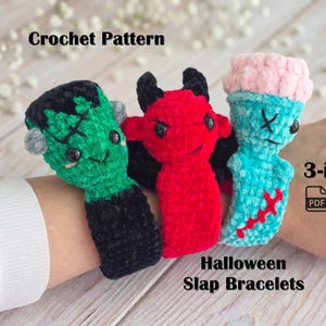 May include: Three crochet slap bracelets featuring Halloween-themed characters: a green Frankenstein monster, a red devil, and a light blue zombie. The text reads Crochet Pattern, 3-in-1, and Halloween Slap Bracelets. The items are made of plush yarn.