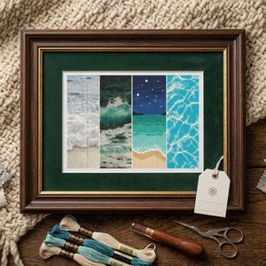Può includere: Opera d'arte a punto croce incorniciata raffigurante scene oceaniche. La cornice in legno marrone scuro ha un passe-partout verde. Il punto croce mostra onde, una notte stellata e riflessi d'acqua. Filo da ricamo, forbici ed etichetta su una superficie di legno.