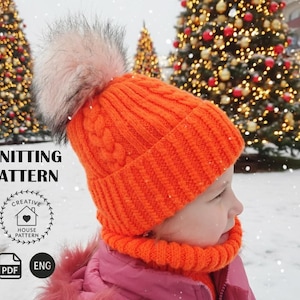 May include: An orange knitted hat and neck warmer set with a fluffy pink pom-pom. The hat has a cable knit design. The image includes the text "KNITTING PATTERN" and a logo.