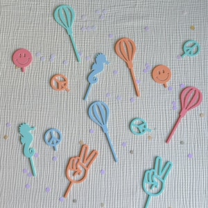 May include: Assortment of colorful party decorations, including peace signs, hot air balloons, seahorses, and smiley faces. The decorations are made of cardboard and have sticks attached to the back for easy placement.