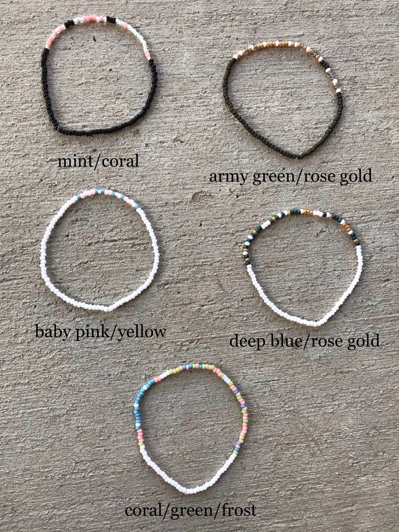 May include: Five beaded bracelets in different color combinations. The bracelets are made with small white beads and feature different colored beads, including mint, coral, army green, rose gold, baby pink, yellow, deep blue, and frost.