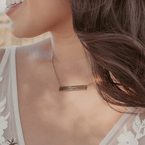 May include: A gold necklace with a bar pendant engraved with the name "Megan".